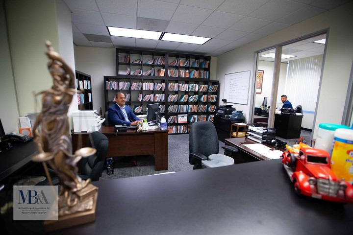 Attorney in blue suit at desk with Lady Justice statue and organized files representing dedicated employment discrimination legal services in Sherman Oaks California