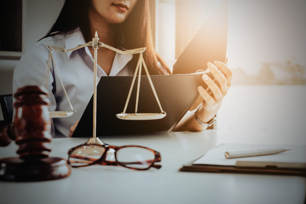Female attorney holding folder with scales of justice and gavel on desk symbolizing fair representation for workplace injury and illness victims in Sherman Oaks California
