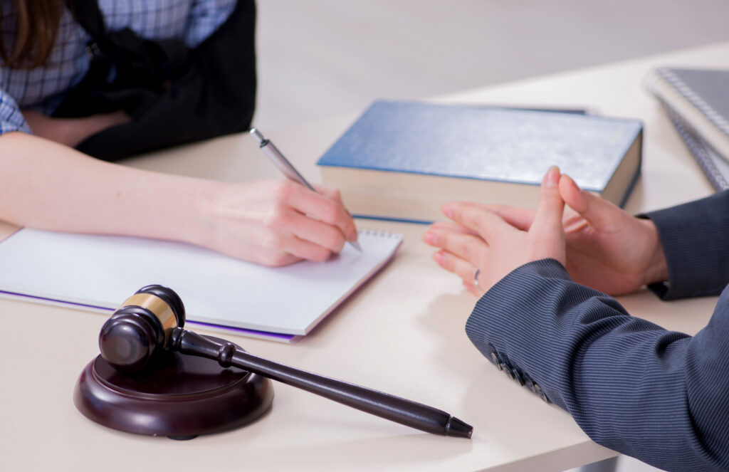 Professional attorney and client discussing personal injury case across desk with gavel notebook and law books in Sherman Oaks California law office