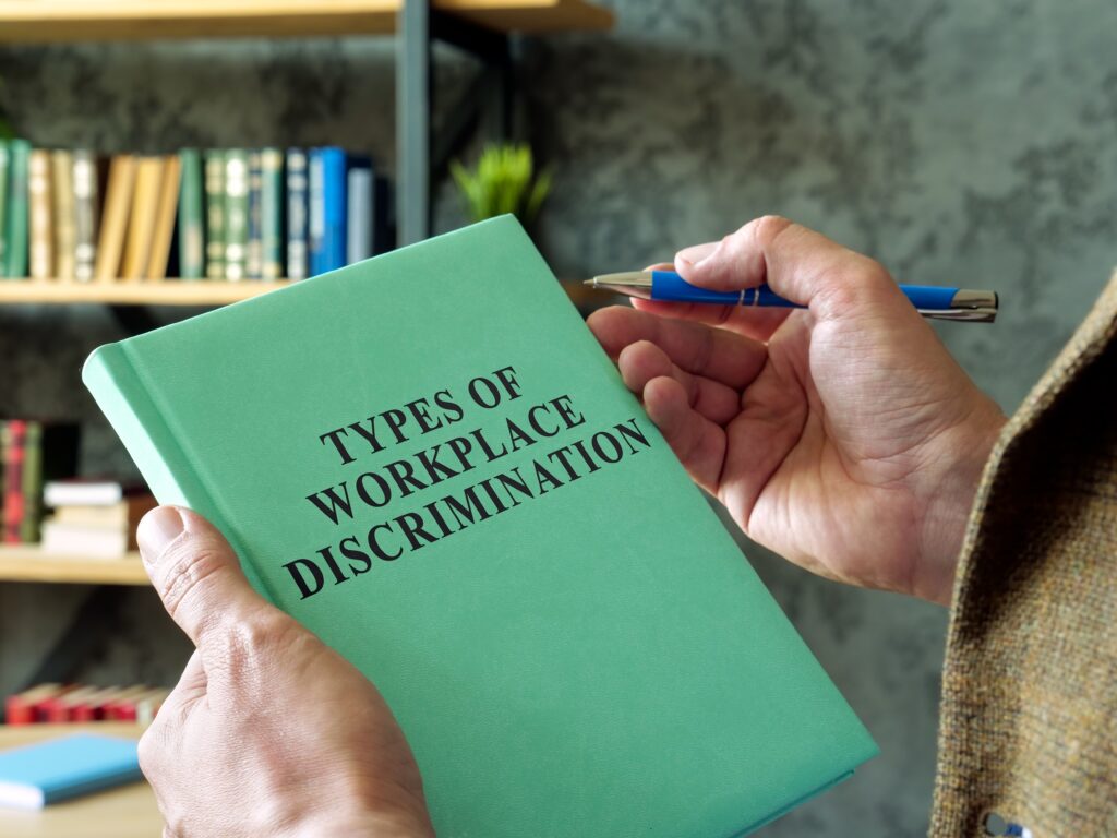 Close-up of green book titled Types of Workplace Discrimination held in office library setting illustrating common employment discrimination issues in Sherman Oaks California
